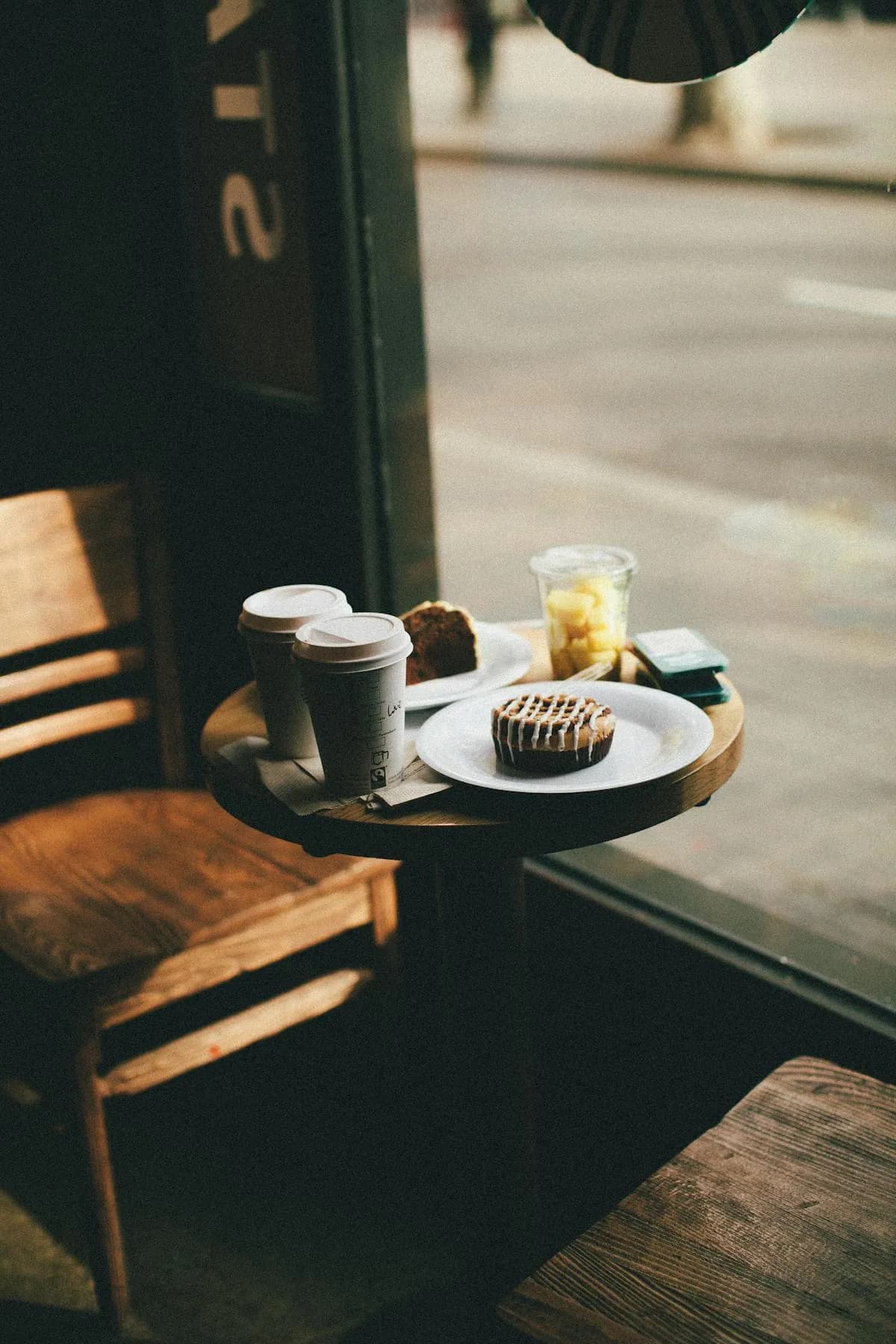 Une table près de la vitrine avec un café et une pâtisserie